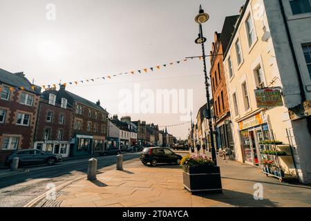 Dunbar, East Lothian , écosse - 13 août 2023 vue générale de Sunlit High Street avec des bâtiments peints et des pots de fleurs en fleurs en premier plan. Bonjour Banque D'Images