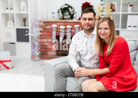 Un couple dans des tenues de vacances élégantes est assis sur un canapé gris Banque D'Images