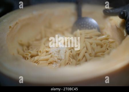 Pasta aus einem Parmesanlaib, Food, Deutschland, Rhénanie-Palatinat, 02.10.2023, das Bild zeigt eine Küchenszene, die eine kulinarische Tätigkeit darstellt. Der zentrale Fokus liegt auf einem Parmesanlaib mit Pasta, die mit einem Metalllöffel umgerührt wird. *** Pâtes à partir d'un pain de parmesan, alimentation, Allemagne, Rhénanie-Palatinat, 02 10 2023, l'image montre une scène de cuisine représentant une activité culinaire. l'accent est mis sur une miche de parmesan avec des pâtes agitées avec une cuillère en métal Credit : Imago/Alamy Live News Banque D'Images