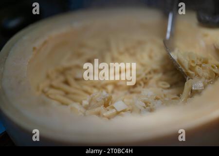 Pasta aus einem Parmesanlaib, Food, Deutschland, Rhénanie-Palatinat, 02.10.2023, das Bild zeigt eine Küchenszene, die eine kulinarische Tätigkeit darstellt. Der zentrale Fokus liegt auf einem Parmesanlaib mit Pasta, die mit einem Metalllöffel umgerührt wird. *** Pâtes à partir d'un pain de parmesan, alimentation, Allemagne, Rhénanie-Palatinat, 02 10 2023, l'image montre une scène de cuisine représentant une activité culinaire. l'accent est mis sur une miche de parmesan avec des pâtes agitées avec une cuillère en métal Credit : Imago/Alamy Live News Banque D'Images