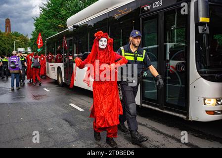 La Haye, pays-Bas. 30 septembre 2023. Le rebelle rouge d'extinction des rébellions, vu arrêté par un officier passant devant le bus, pendant le vingt-deuxième jour du blocus de protestation de l'A12. La police a arrêté samedi 600 militants qui bloquaient partiellement l’A12 à la Haye. Extinction les manifestations de la rébellion ont bloqué la route d'entrée principale de l'A12 pendant vingt-deux jours consécutifs, exigeant du gouvernement qu'il cesse de soutenir l'industrie des combustibles fossiles. La police a utilisé des canons à eau contre les manifestants. Les 600 manifestants ont été emmenés en bus au stade de football ado et RE Banque D'Images