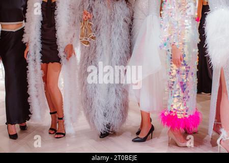 Les mannequins sur les coulisses habillés dans un long boudoir haute couture habillent tenues et talons hauts. Préparation avant le défilé de mode Banque D'Images