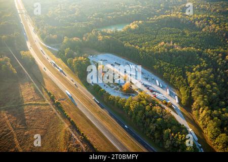 Vue de dessus de la grande aire de repos près de l'autoroute américaine à plusieurs voies très fréquentée avec des voitures et des camions rapides. Lieu de repos de loisir pendant les voyages entre États Banque D'Images