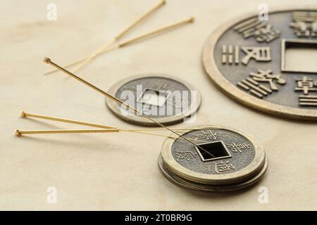 Aiguilles d'acupuncture et pièces de monnaie anciennes sur papier, gros plan Banque D'Images