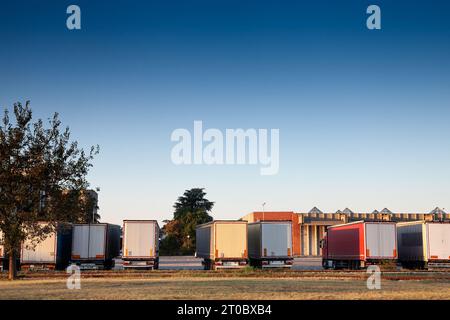 Photo d'une rangée de semi-camions, de camions européens et de camions garés au crépuscule dans un entrepôt serbe à Belgrade, en Serbie. Banque D'Images