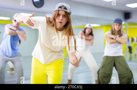 Garçons et filles dansant la chorégraphie de groupe synchrone dans la salle de danse Banque D'Images