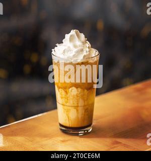 Café au latte caramel dans un grand verre avec sirop et crème fouettée. Banque D'Images