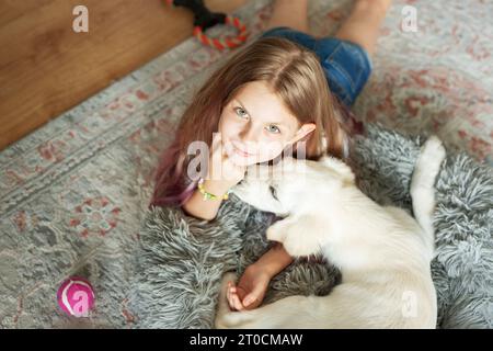 Petite fille jouant avec un chiot Golden retriever à la maison. Amis à la maison. Banque D'Images