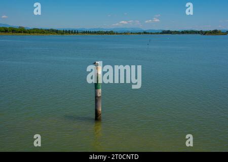 Un marqueur de canal montre le bord d'un canal navigable dans les eaux peu profondes de la section Grado de la lagune de Marano et Grado au Frioul, en Italie Banque D'Images