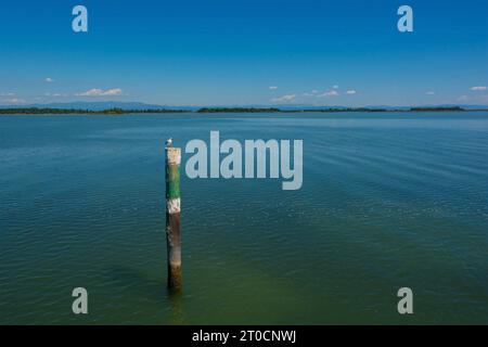 Un marqueur de canal montre le bord d'un canal navigable dans les eaux peu profondes de la section Grado de la lagune de Marano et Grado au Frioul, en Italie Banque D'Images