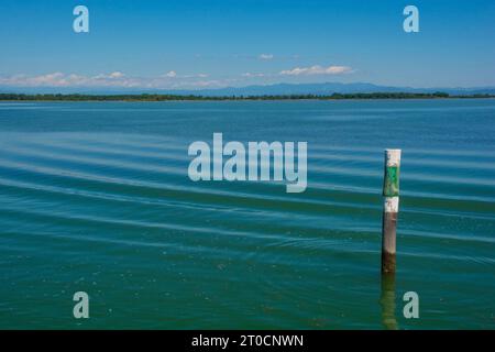 Un marqueur de canal montre le bord d'un canal navigable dans les eaux peu profondes de la section Grado de la lagune de Marano et Grado au Frioul, en Italie Banque D'Images