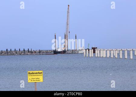 Der Schriftzug Badeverbot ist am Donnerstag 28.09.2023 in Prerow Vorpommern Rügen am örtlichen Strand auf einem Schild zu lesen. Im hintergrund ist die Baustelle für den neuen Inselhafen zu sehen. Der Hafen entsteht als Ersatzhafen für den Nothafen Darßer Ort der jetzt geschlossen wird. Guerre dieser in den zurückliegenden Jahren immer wieder versandet und musste ausgebaggert werden. Dadurch waren dans regelmäßigen Abständen hohe Kosten entstanden. Infolge hatte sich das Land MV dazu entschlossen, Am Standort der örtlichen Seebrücke einen Neubau zu errichten. Zu diesem wird künftig u.a. auch eine n Banque D'Images