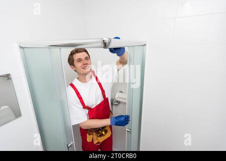 Les Ouvriers Installent Un Joint D'étanchéité En Silicone Sur La Porte  Vitrée De La Cabine De Douche.