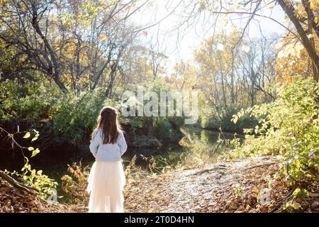 Fille en robe de tulle brille près d'un lac d'automne éclairé par le soleil Banque D'Images