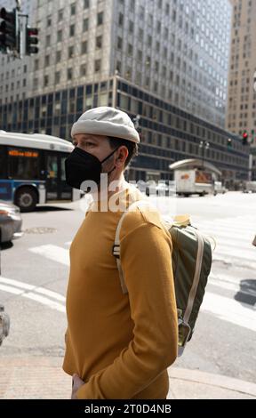 Homme prudent en masque observe avant de traverser la rue de la ville Banque D'Images