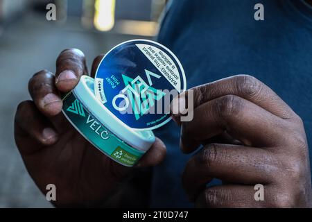 Nakuru, Kenya. 06 octobre 2023. Une main tient un récipient en plastique de la marque de nicotine Velo de British American Tobacco (BAT) à Nakuru. Le Parlement kenyan débat de l'imposition d'une interdiction de la marque Velo de sachets de nicotine fabriqués en Hongrie par British American Tobacco, avec des préoccupations découlant de la dépendance à la substance et des effets nocifs potentiels sur la santé des utilisateurs. Crédit : SOPA Images Limited/Alamy Live News Banque D'Images