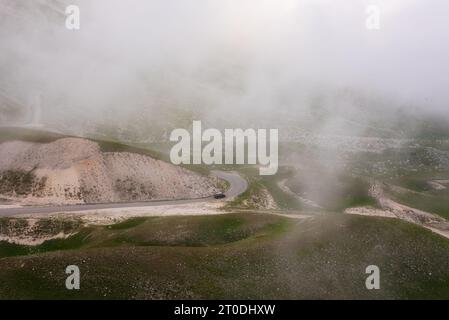 Route sinueuse avec une voiture dans la montagne parmi les nuages Banque D'Images