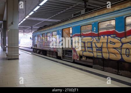 Un vieux train parsemé de graffitis traverse la gare principale souterraine de Prokop à Belgrade, en Serbie Banque D'Images