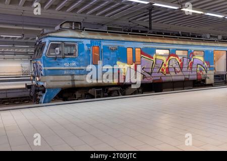 Un vieux train parsemé de graffitis traverse la gare principale souterraine de Prokop à Belgrade, en Serbie Banque D'Images