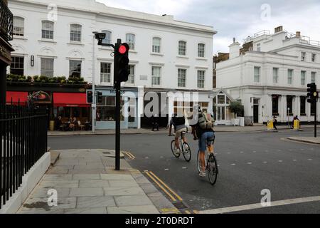 Cyclistes qui courent à travers les feux rouges sur Sydney Street sur Fulham Road Chelsea Londres Angleterre Banque D'Images