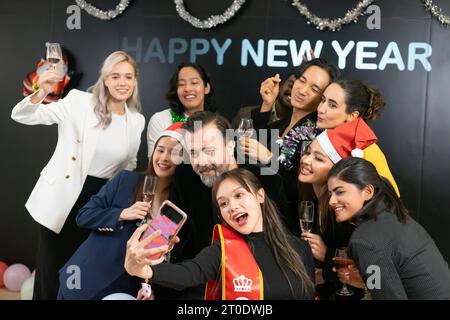 Prenons un selfie !! Un groupe de gens d'affaires divers et collègues s'amusant ensemble à une fête du nouvel an d'affaires. Une célébration de travail d'équipe d'un Banque D'Images