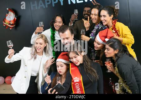 Prenons un selfie !! Un groupe de gens d'affaires divers et collègues s'amusant ensemble à une fête du nouvel an d'affaires. Une célébration de travail d'équipe d'un Banque D'Images