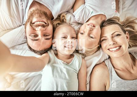 Heureux, amour et portrait de la famille sur un lit pour lier et se détendre ensemble à la maison moderne. Bonheur, sourire et vue de dessus des fillettes couchées Banque D'Images