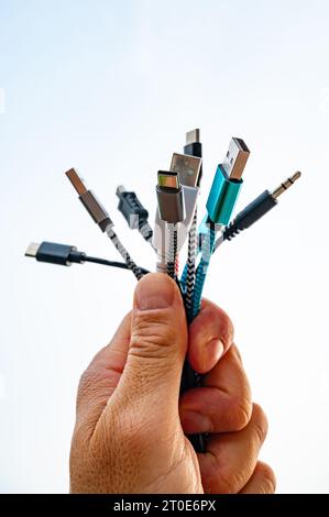 Main tenant différents types de câbles avec prises USB, évolution et changement des connexions USB. Banque D'Images