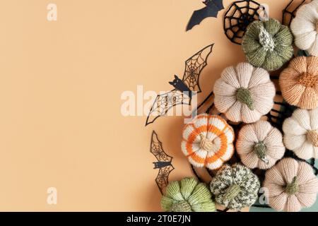 Maquette de carte de voeux Halloween avec espace de copie. Décorations d'Halloween, chauves-souris, toiles tricotées, citrouilles sur fond beige. Pose à plat, vue de dessus Banque D'Images