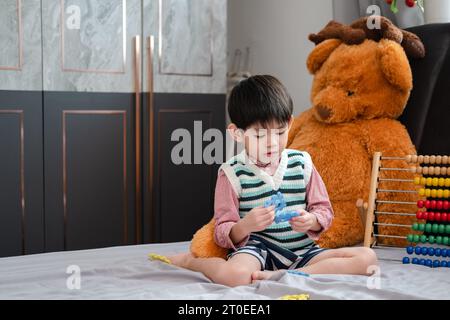 Garçon asiatique jouant avec des puzzles sur le lit joyeusement Banque D'Images