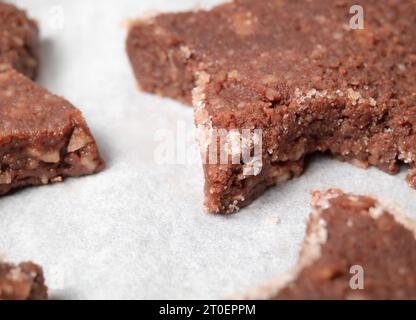 Biscuit au chocolat sur papier parchemin. Biscuit au chocolat à la farine d'amande sans gluten avec rebord cannelle de sucre, forme d'étoile. Recette suisse 'Basler Brunsli'. CHR Banque D'Images