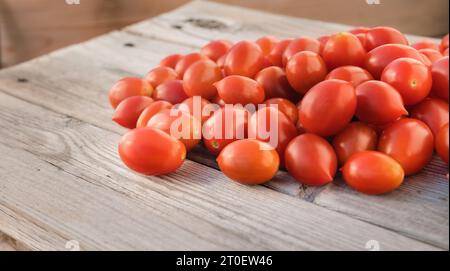 Tomates cerises de raisin sur fond en bois. Vue en perspective de tomates mûres rouges fraîchement cueillies sur la table en bois. Pile aléatoire de raisins sucrés t Banque D'Images