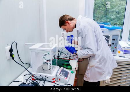 Scientifique avec la main gantée plaçant l'échantillon d'ADN dans PCR-cycler en temps réel. Banque D'Images