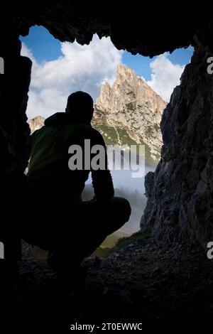 Italie, Vénétie, province de Belluno, Cortina d'Ampezzo, le Sass de Stria / Hexenstein ou Hexenfels, un homme en silhouette regardant d'une grotte de guerre, Dolomites Banque D'Images