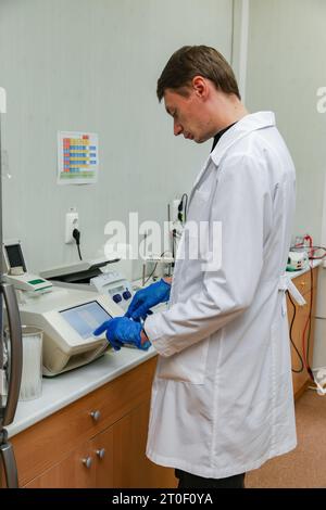 Scientifique avec la main gantée plaçant l'échantillon d'ADN dans PCR-cycler en temps réel. Banque D'Images