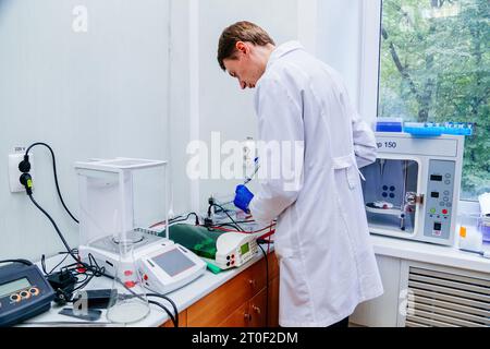 Scientifique avec la main gantée plaçant l'échantillon d'ADN dans PCR-cycler en temps réel. Banque D'Images