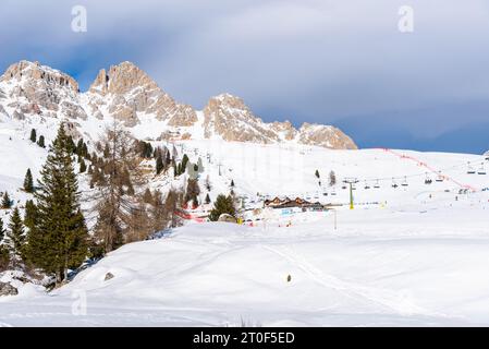 Remontées mécaniques et pistes de ski au pied d'imposants sommets rocheux enneigés dans les Dolomites par une journée ensoleillée d'hiver Banque D'Images