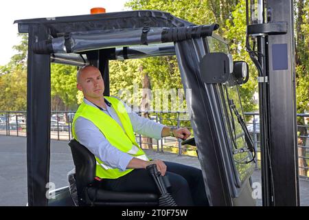 Conducteur chauve avec gilet de sécurité jaune dans la cabine du chariot élévateur Banque D'Images