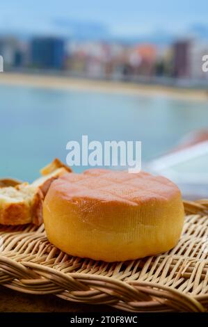 Fromage de vache fumé espagnol de Pria, Asturies, servi en plein air avec vue sur la plage de San Lorenzo et la promenade de Gijon Banque D'Images