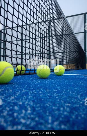 quatre balles de paddle-tennis à côté du filet sur un court de gazon artificiel bleu, concept de sports de raquette Banque D'Images