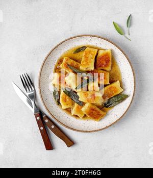 Gnocchi maison italien avec pommes de terre, fromage et beurre de sauge, servi dans une assiette sur une table lumineuse. Cuisine italienne Banque D'Images