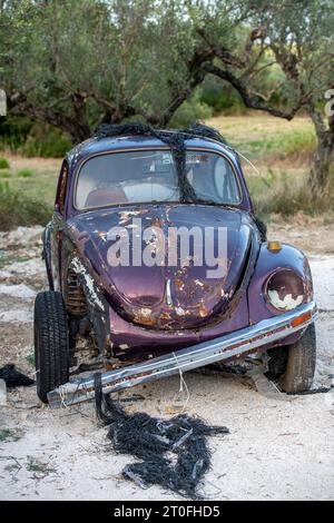 épave rouillée ou corrodée d'une voiture à moteur vintage volkswacen beetle abandonnée dans un champ plein d'oliviers en grèce. Banque D'Images