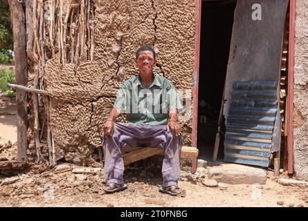 Un vieil homme san du Kalahari central, village de New Xade au Botswana, devant sa maison de boue après son déménagement Banque D'Images