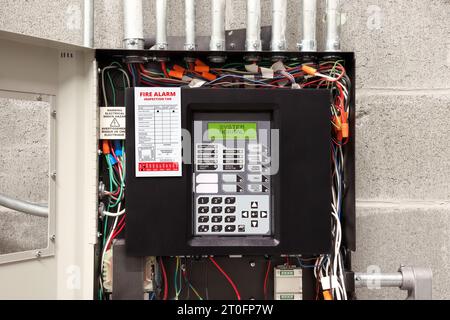 Panneau de commande d'alarme incendie dans la salle de service avec étiquette d'inspection incendie. Armoire ouverte de système d'alarme incendie à une étape dans strata, résidentiel ou commercial Banque D'Images