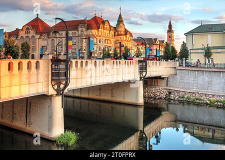 Heure d'or à Oradea, Roumanie avec le palais de l'aigle noir dans le style architectural sécession dominant un autre pont art nouveau sur le Rapid Cris r Banque D'Images