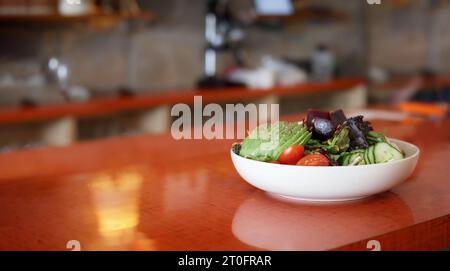 Grand saladier sur la table avec fond de restaurant défocalisé. Repas diététique ou repas végétarien. Salade avec variété de légumes tels que l'avocat Banque D'Images