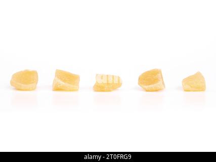 Morceaux isolés de gingembre confit dans une rangée. Morceaux jaunes de gingembre confit ou cristallisé. Snack sain pour aider avec le système digestif, mouvement malade Banque D'Images