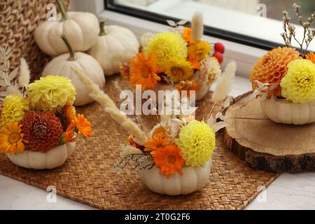 Composition avec de petites citrouilles, de belles fleurs et des épillets sur le rebord de la fenêtre à l'intérieur Banque D'Images