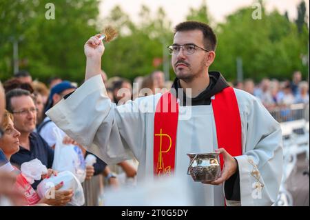 Un prêtre bénit les articles religieux des fidèles après la Messe du soir à Medjugorje. Banque D'Images