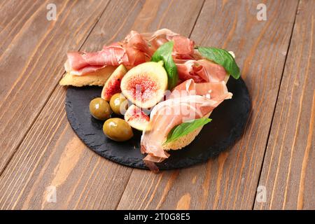 Planche de sandwichs savoureux avec prosciutto sur fond en bois Banque D'Images